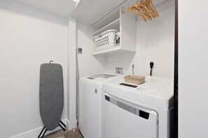 A laundry area with a dryer, a washing machine, and a hanging rack.