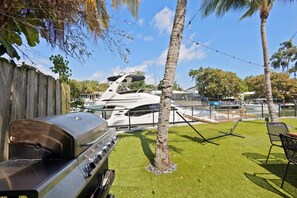 A backyard with a barbecue grill, a hammock, and a pool area with boats. - Waterfront Pool I Dock, Paddleboards, & Fishing (Miami)