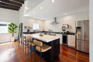 A modern kitchen with a central island, stainless steel appliances, and a large window. - Waterfront Pool I Dock, Paddleboards, & Fishing (Miami)