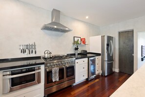 A modern kitchen with stainless steel appliances, a gas stove, oven, and a built-in range hood.