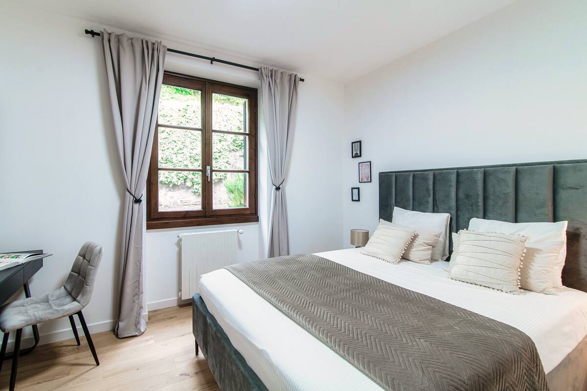 A bedroom with a bed, a desk, and a chair.