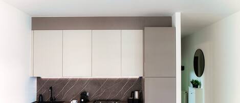 A modern kitchen with a marble backsplash, stainless steel appliances, and a pendant light.