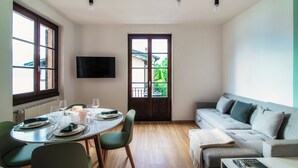A dining area with a table set for four, a sofa, and a TV mounted on the wall. - Monsignor Houses (Menaggio)