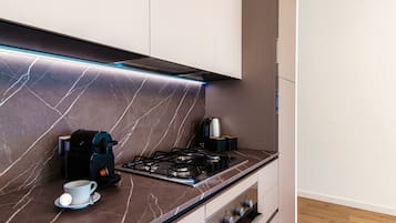 Una cocina moderna con estufa a gas, cafetera y una taza sobre la encimera.