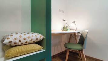 A room with a bed, a desk with a lamp, and a chair.
