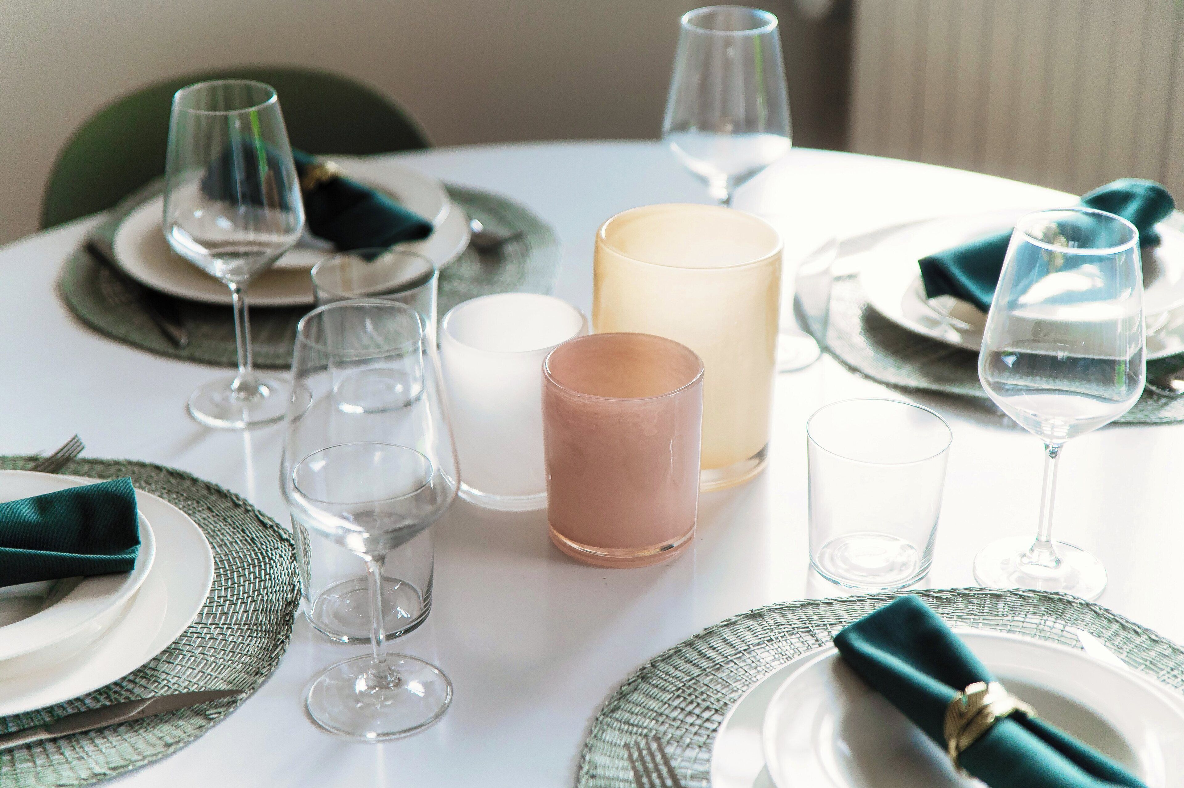 A table set for a meal with clear glassware, plates, and a candle.