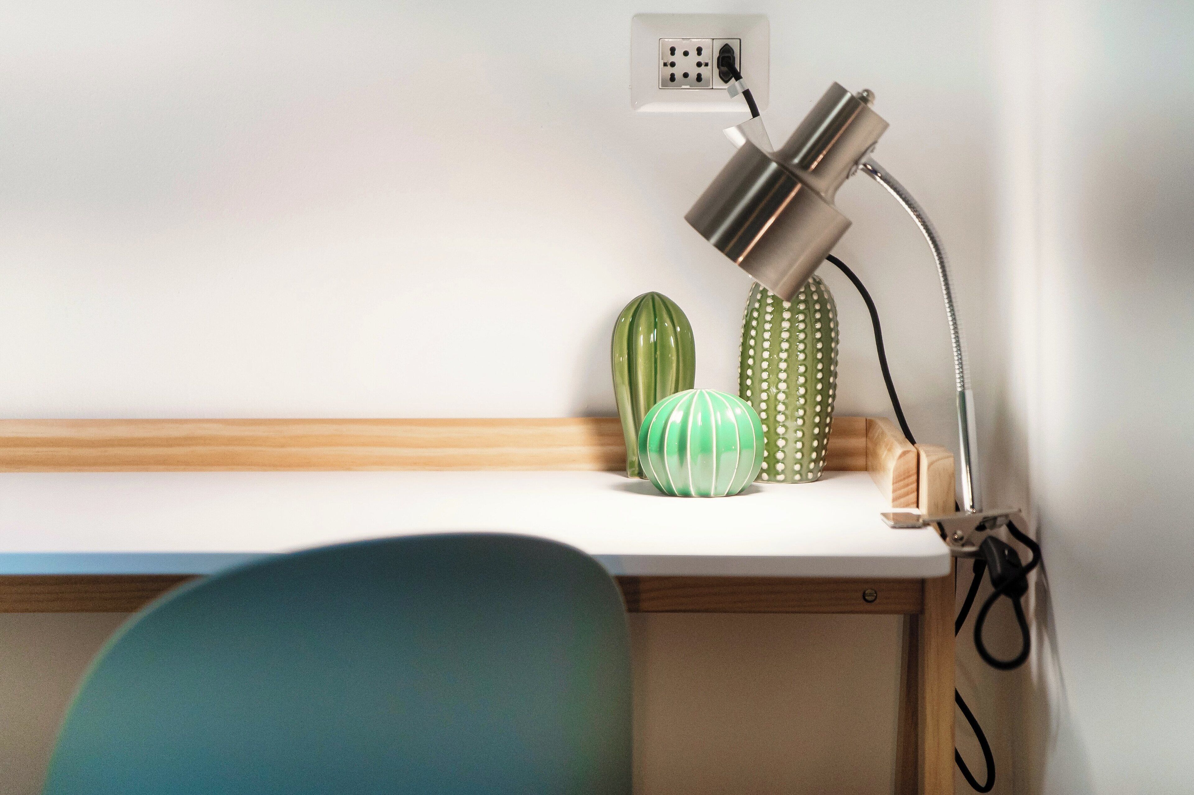 Ein Schreibtisch mit Lampe, Kaktee und einem Holzgegenstand.