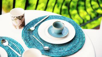A table set with a blue woven placemat, a white plate, a blue cup, and a silver spoon.