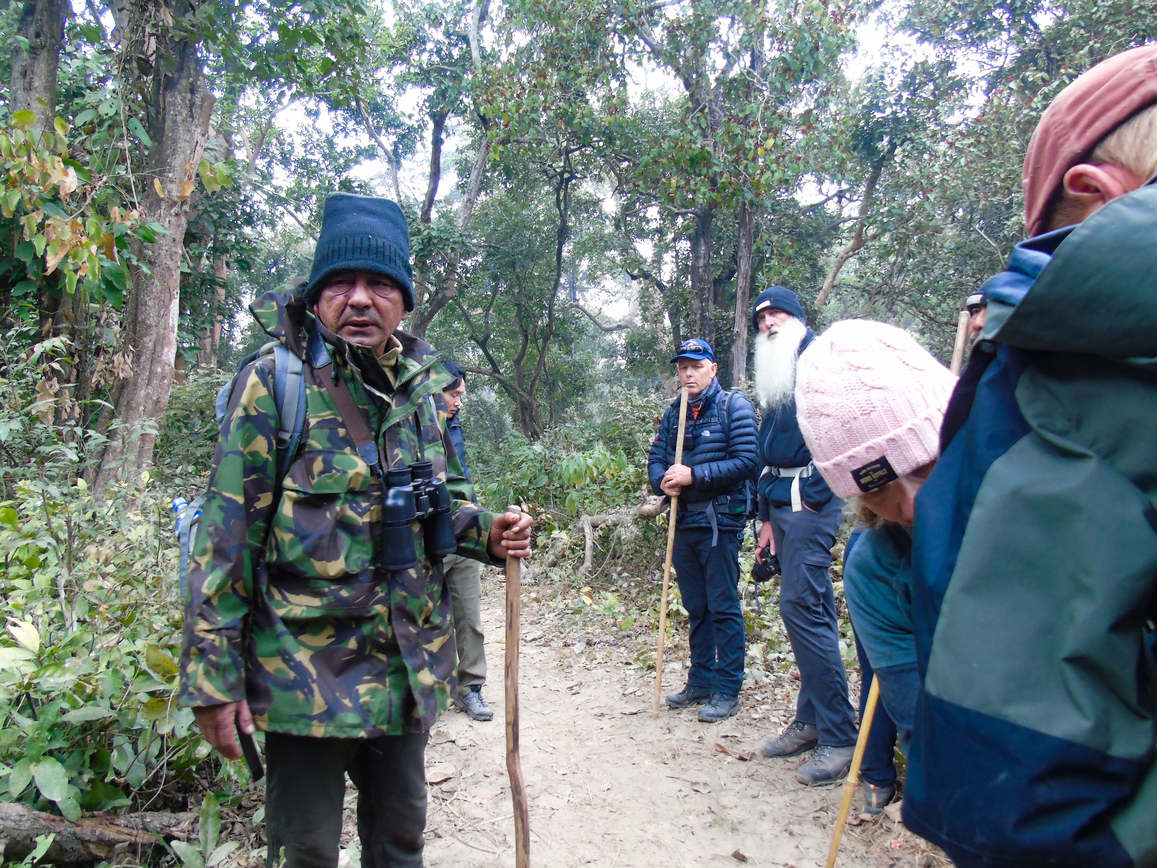 Un grupo de personas en una zona boscosa, algunas vestidas con ropa de exterior y sombreros.