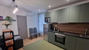 A compact kitchen with a microwave, stove, and modern cabinetry. There is a small dining area with two chairs and a table. - Appartement 3 (Viry-Châtillon)