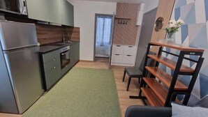 A compact kitchen with modern appliances, a dining area with a bench, and a small seating space. - Appartement 3 (Viry-Châtillon)