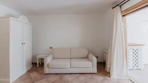Ett minimalistiskt rum med en beige soffa, ett litet bord och en garderob.