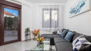 A modern living room with a glass coffee table, grey sofa, and a large window with sheer curtains. - Apartment Isola with terrace and parking (Rovinj)