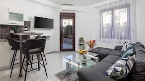 A modern apartment with a kitchen, dining area, and living room. It includes a flat-screen TV, a sofa, and a coffee table. - Apartment Isola with terrace and parking (Rovinj)