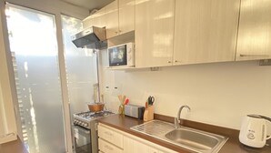 Une cuisine moderne avec des meubles en bois, un évier en acier inoxydable et un four à micro-ondes encastré.