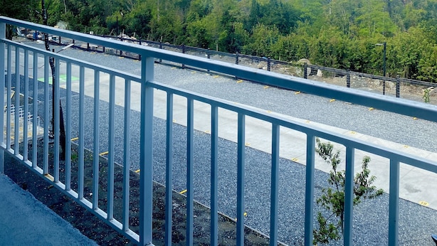 Une vue depuis un balcon doté d’une balustrade, donnant sur un parking et un paysage montagneux.