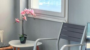 A room with a window, a potted orchid, a wooden table, and a chair. - Alimos Sea View Family Apartment (Alimos)