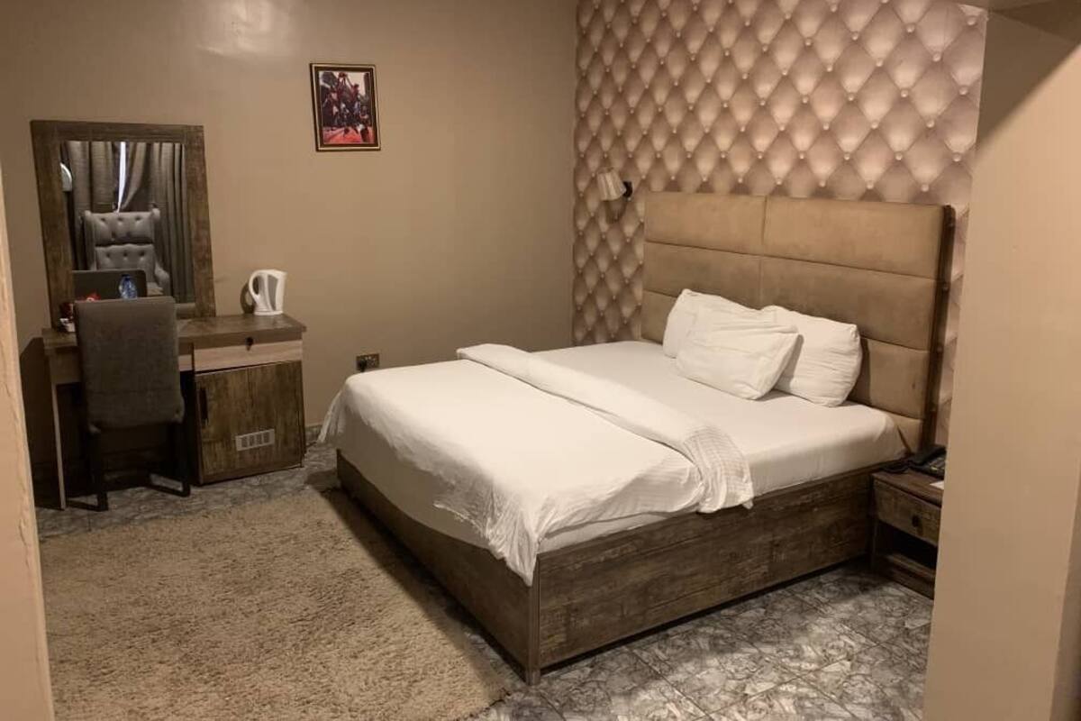 A bedroom with a bed, a desk, and a chair.