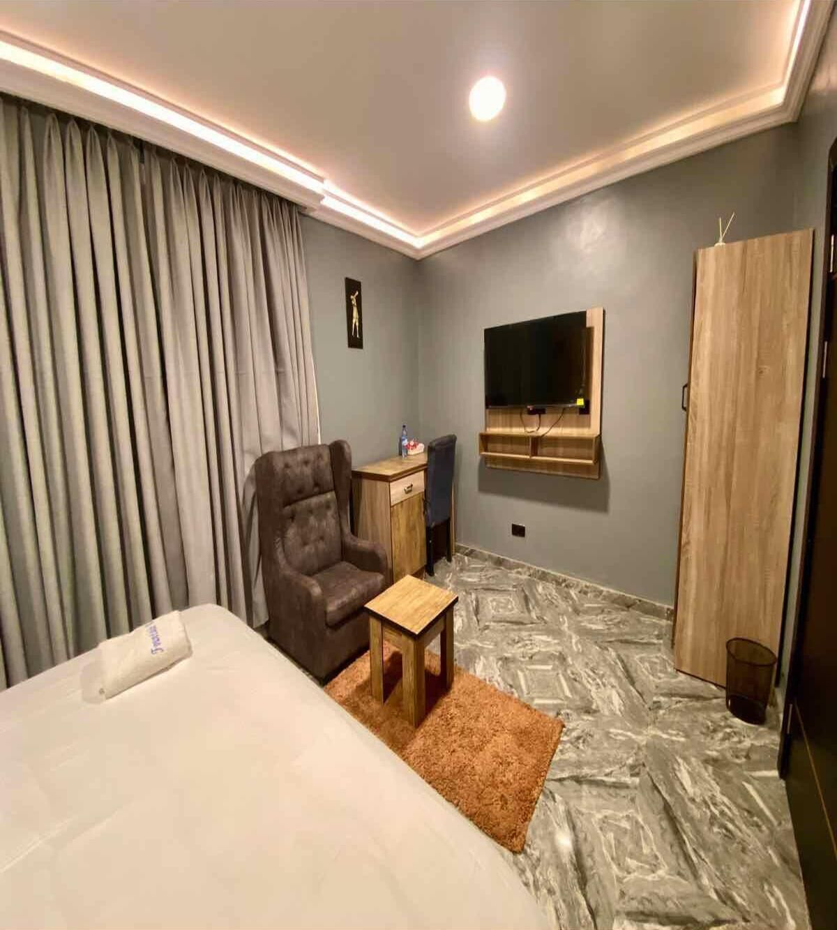 Habitación de hotel con cama, escritorio, silla, televisión y armario.