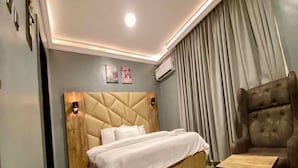 Un dormitorio moderno con una cama grande, una mesita de noche de madera, una pequeña mesa de madera y un sillón mullido.