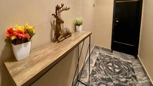 Un área de recepción con un mostrador de madera, una escultura decorativa de un ciervo y una planta en maceta.
