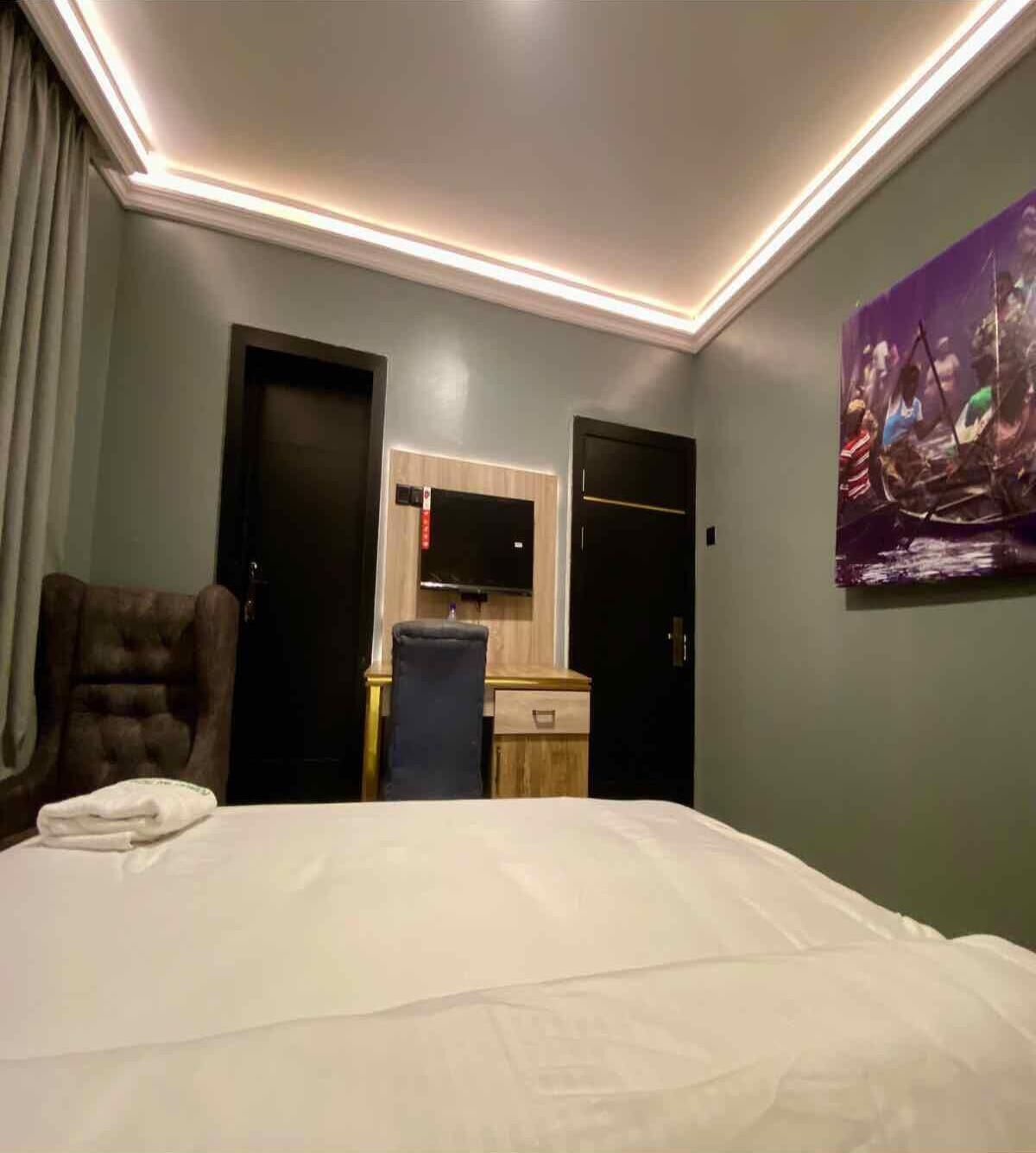 Une chambre d’hôtel avec un grand lit, un bureau avec une chaise, un téléviseur à écran plat et un tableau au mur.