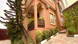 Una casa de dos plantas con un balcón, una escalera y un jardín.