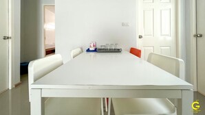 A dining area with a white table and chairs, a tray with glasses, and a door with a light switch. - GAO Akira Pool Villa (Ban Chang)