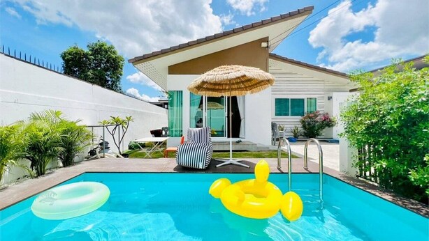 A swimming pool with inflatable rings, a chair, and a thatched umbrella. - GAO Akira Pool Villa (Ban Chang)