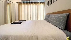 A hotel room with a bed, a headboard, a wall-mounted air conditioner, a window with curtains, and framed pictures on the wall. - GAO Akira Pool Villa (Ban Chang)