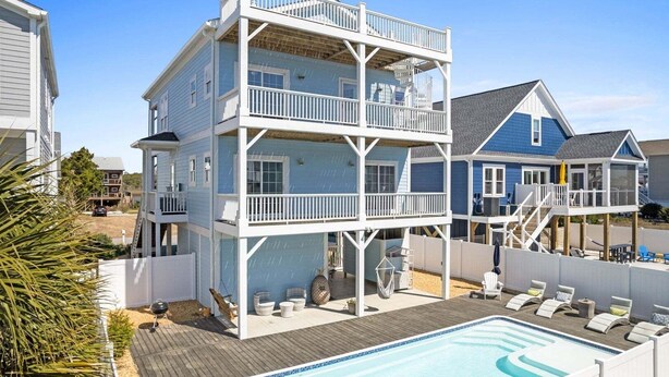 Une maison à plusieurs étages dotée d’une piscine, d’un espace salon extérieur et d’une terrasse.