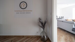 A modern interior with a wooden floor, a grey sofa, and a vase with feathers.