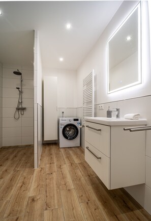 Ein modernes Badezimmer mit Waschmaschine, Waschbecken und Spiegel.
