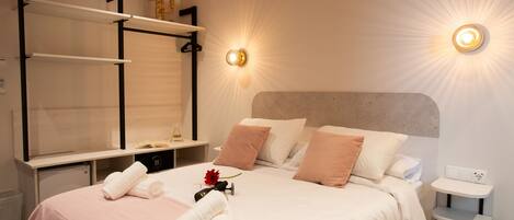 A neatly arranged hotel room with a bed, bedside tables, a vanity with a mirror, and wall-mounted lights.