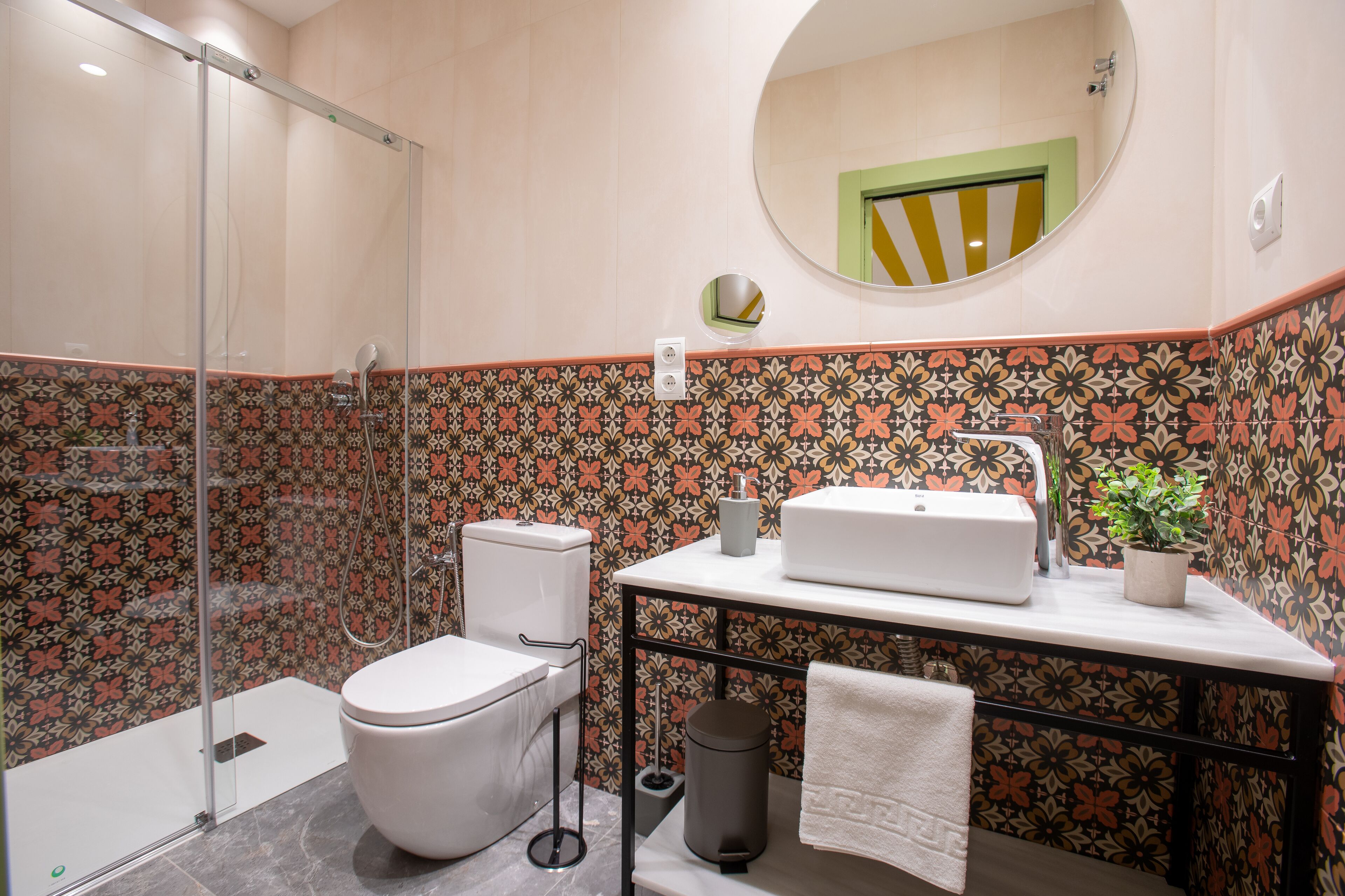 A bathroom with a shower, toilet, sink, and a mirror.