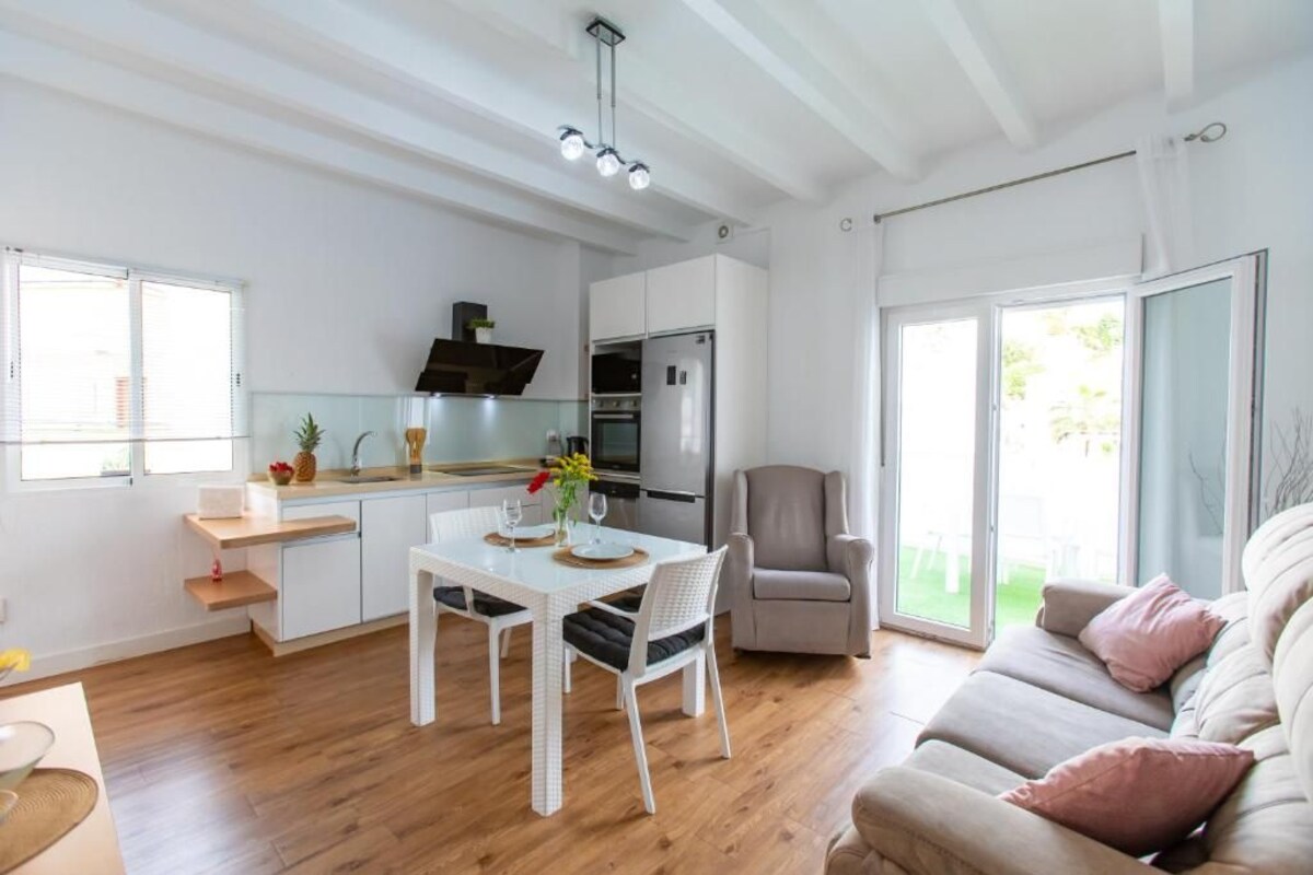 A modern kitchen with white cabinetry, a dining table with chairs, and a large window providing natural light.