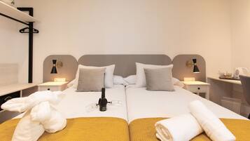 A double bed with two pillows, a bedside table with a lamp, and a bottle of champagne.