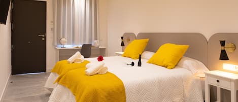 Una habitación de hotel con una cama grande, una mesita de noche, un escritorio y una silla.