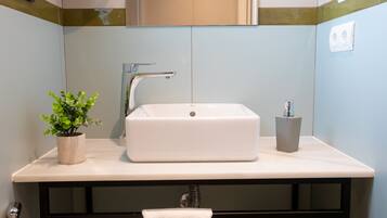A bathroom with a white sink, a potted plant, and a towel hanging on a rack.