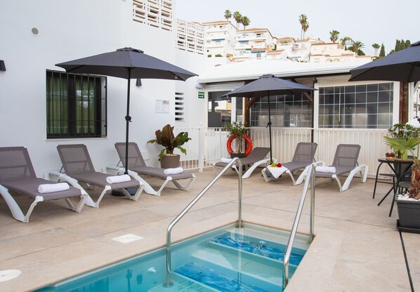 Un espace piscine avec des chaises longues et des parasols.