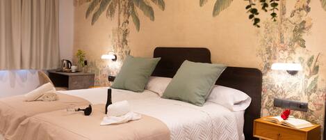 Habitación de hotel con una cama grande, dos mesitas de noche y una pared con un mural tropical.