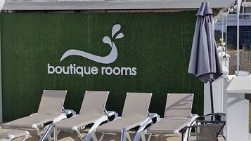 A wall with a logo and text reading "boutique rooms" and a row of lounge chairs.