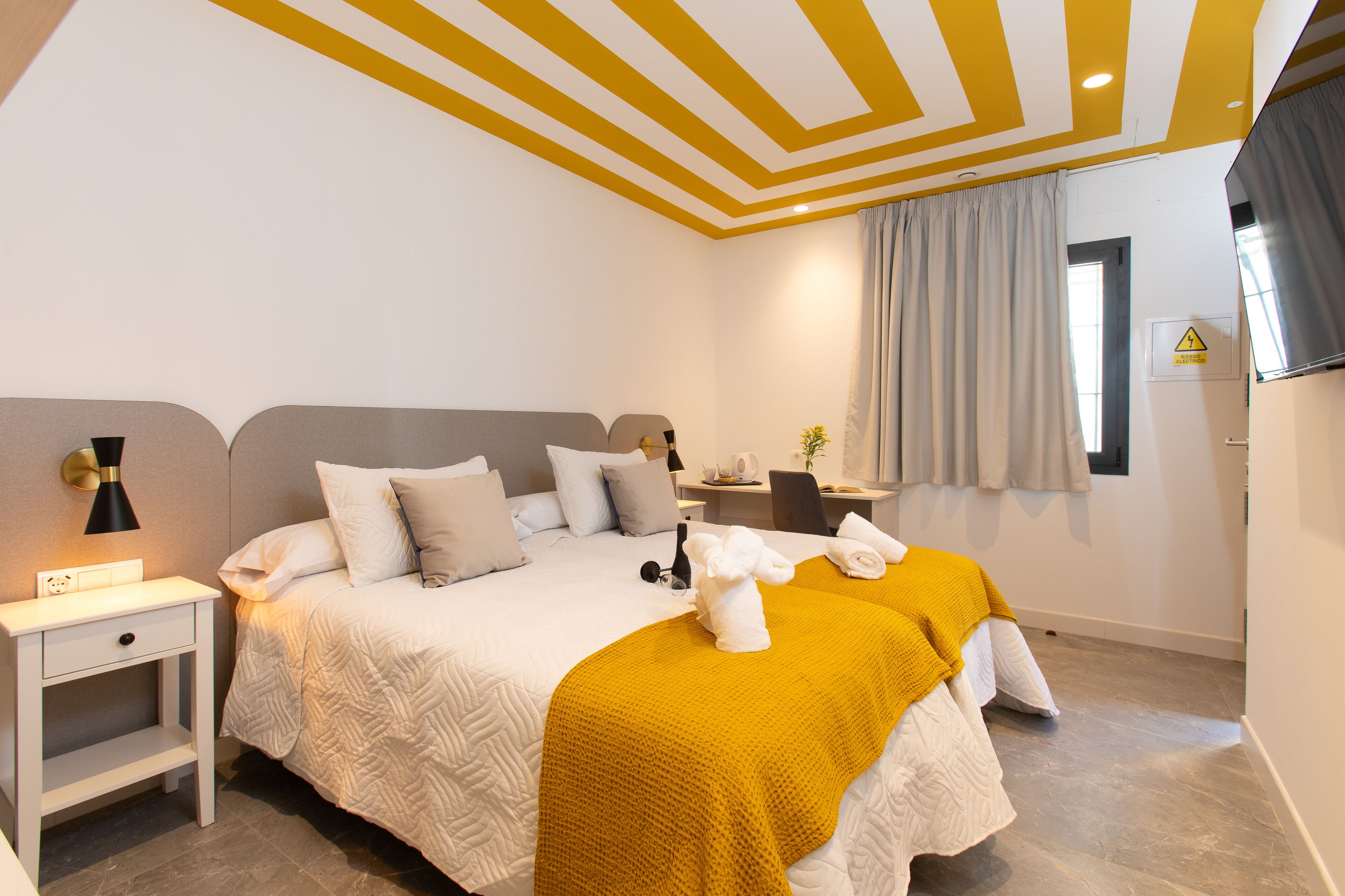 A hotel room with a large bed, bedside tables, a desk, and a chair.