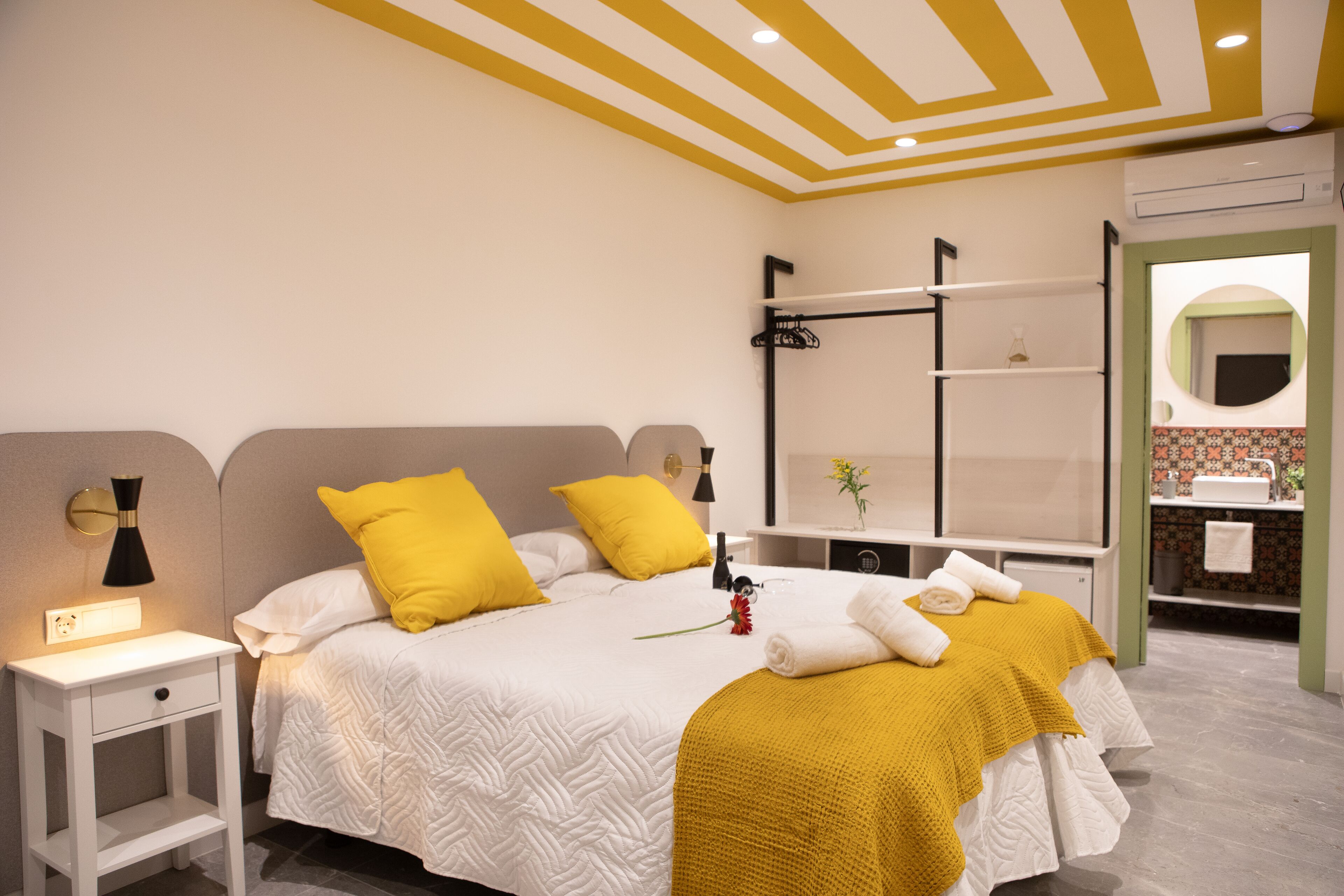 Une chambre à coucher bien rangée, avec un lit, des tables de chevet et un miroir.