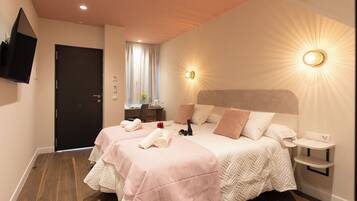 Une chambre d’hôtel avec un grand lit, deux tables de chevet, un téléviseur fixé au mur et une fenêtre avec des rideaux.