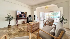 Ein geräumiges Wohnzimmer mit Fernseher, einer Kaffeemaschine und Blick ins Freie.