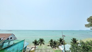 Blick auf die Küste mit blauem Himmel, einem Schwimmbad und Palmen.