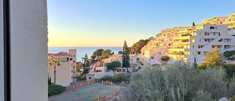 Zona residencial costera con edificios, cielo despejado y vista al mar.