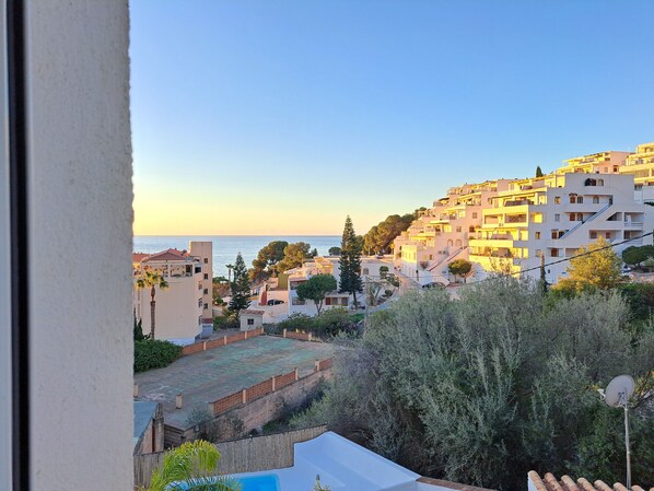 A coastal residential area with buildings, a clear sky, and a view of the sea.