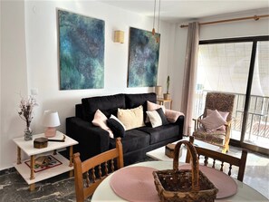 Relax in this stylish living room with a sofa, chair, and balcony offering a view of the outdoors.